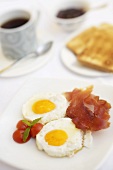 Fried eggs with bacon and tomatoes, toast and coffee
