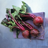 Three beetroots with leaves on a fabric napkin