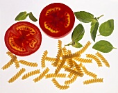 Pasta, tomato slices and basil on sheet of glass
