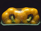 Two yellow peppers in packaging with drops of water