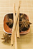 Star anise and cinnamon sticks in wooden bowl