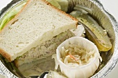 Tuna sandwich with coleslaw and gherkin in lunch box