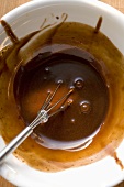 Chocolate sauce with whisk in white bowl