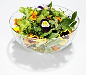 Salad leaves with flowers in glass bowl