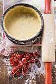 Baking tin lined with pastry, redcurrants and rolling pin