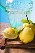 Fresh lemons with leaves in front of water jug