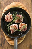 Goat's cheese wrapped in bacon in frying pan on flatbread