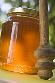 Jar of honey with honey dipper on table in the open air