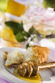 Honey with honey dipper and remains of croissant on plate