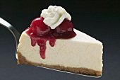 Slice of cheesecake with cherries and cream on cake server