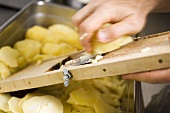Slicing cooked potatoes with vegetable slicer