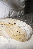 Making olive bread (sprinkling with flour)