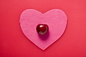 A cherry on a pink fabric heart