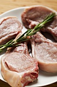 Raw pork chops with rosemary on plate