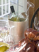 White wine bottle in ice bucket, wine glasses, lobster, lemon