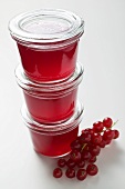 Three jars of redcurrant jelly with fresh redcurrants