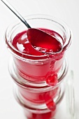 Three jars of redcurrant jelly, one opened, with spoon