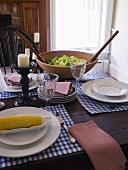 Laid table with corn cob and salad (USA)