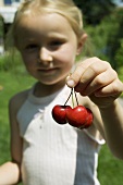Blond girl holding three cherries