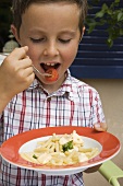 Small boy eating pasta with tomatoes