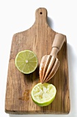 Two lime halves, one squeezed, on chopping board