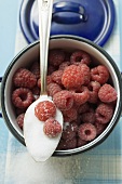 Raspberries in a pan and spoonful of sugar (overhead view)