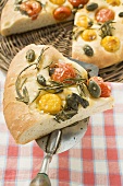 Pizza with cherry tomatoes, capers & rosemary (a slice cut)