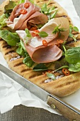 Parma ham, herbs and chili rings on pizza bread