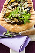 Grilled aubergine slices and herbs on pizza bread