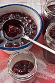 Ladling cherry jam into jars