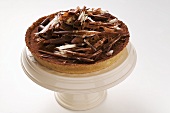 Whole chocolate tart with chocolate curls on cake stand
