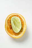 Squeezed lime half inside squeezed orange half