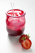 Jar of strawberry jam with spoon, fresh strawberries