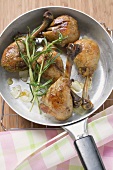 Fried chicken legs with rosemary in frying pan