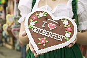 Woman in national dress holding Lebkuchen heart at Oktoberfest