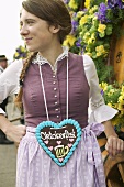 Woman in national dress with Lebkuchen heart at Oktoberfest