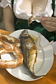 Woman eating Steckerlfisch (skewered fish) with pretzel, Oktoberfest