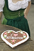 Lebkuchen heart on rustic table, woman in background