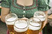 Waitress in national dress serving four litres of beer (Oktoberfest)