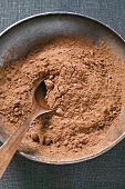 Cocoa powder in bowl with wooden spoon