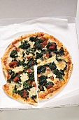 Spinach, tomato and cheese pizza in pizza box
