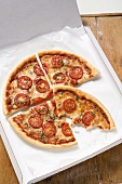 Cheese & tomato pizza with oregano (quartered) in pizza box