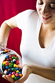 Woman tipping bubble gum balls out of a jar into her hand
