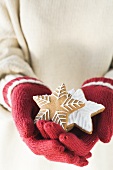 Hands in woollen gloves holding gingerbread stars