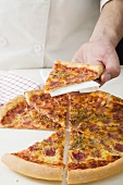 Koch hält Stück Schinkenpizza (amerikanische Art)