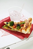 Two slices of American-style vegetable pizza, mineral water