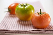 Three different tomatoes on tea towel