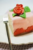 Piece of birthday cake with marzipan roses on plate