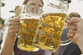 Hände stossen mit zwei Mass Bier an (München, Oktoberfest)