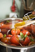 Pouring olive oil over tomato salad